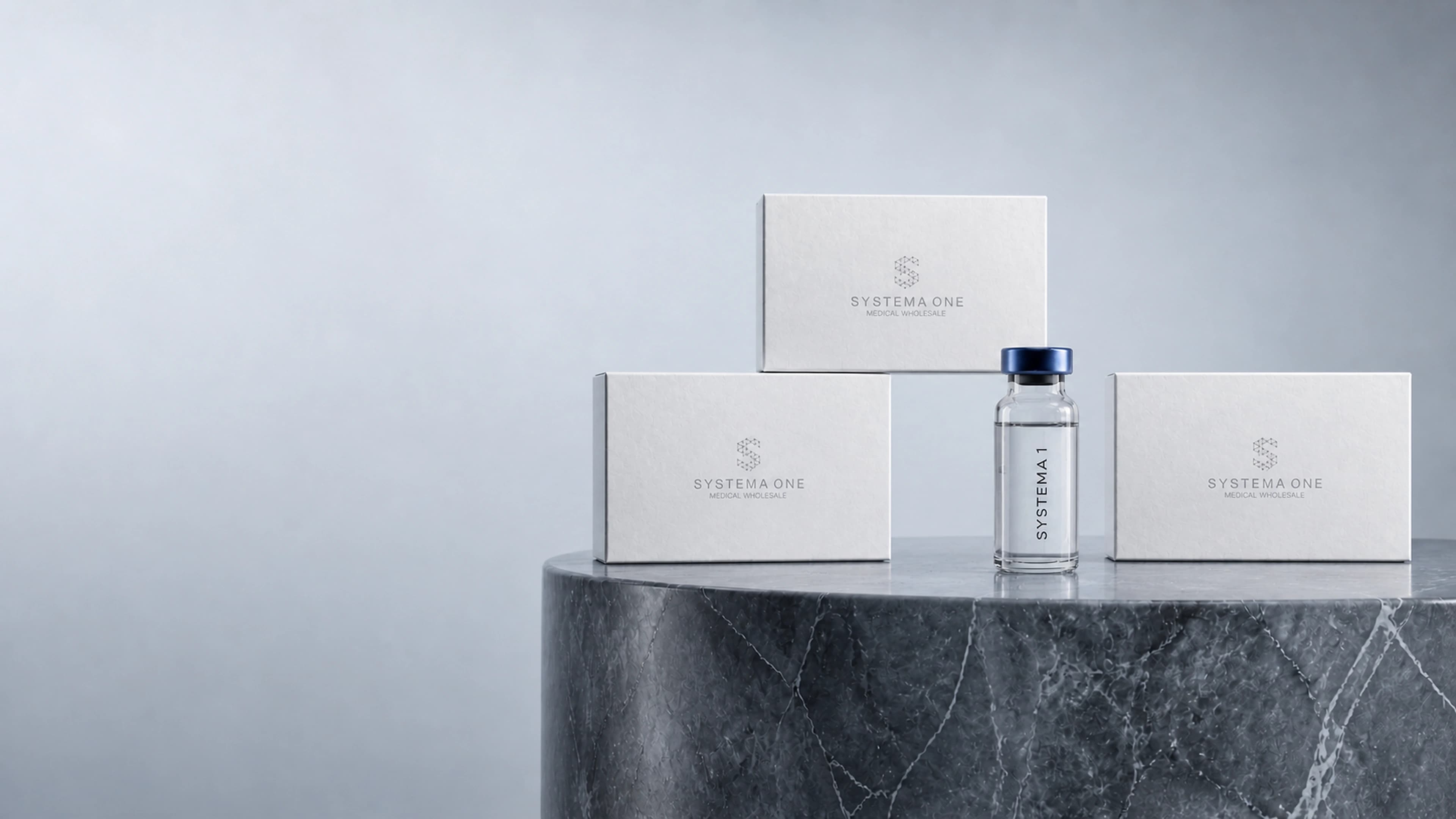 A clear Systema 1 vial and branded presentation cases arranged on a continuous Carrara marble display